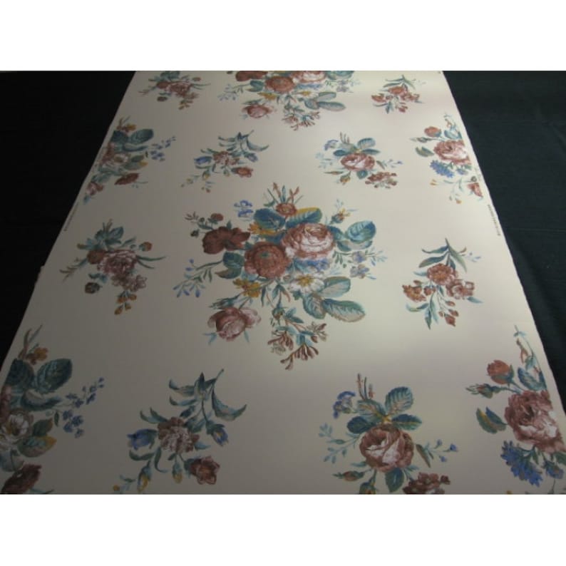 May include: A vintage wallpaper with a repeating pattern of brown and white roses with green leaves on a cream background.