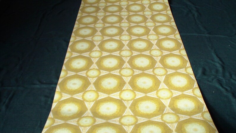 May include: A close-up of a wallpaper roll with a repeating pattern of white and yellow circles with a geometric design. The wallpaper has a vintage look and feel.