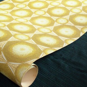 May include: A roll of wallpaper with a repeating pattern of yellow and white circles. The circles are arranged in a geometric pattern and have a slightly textured surface.