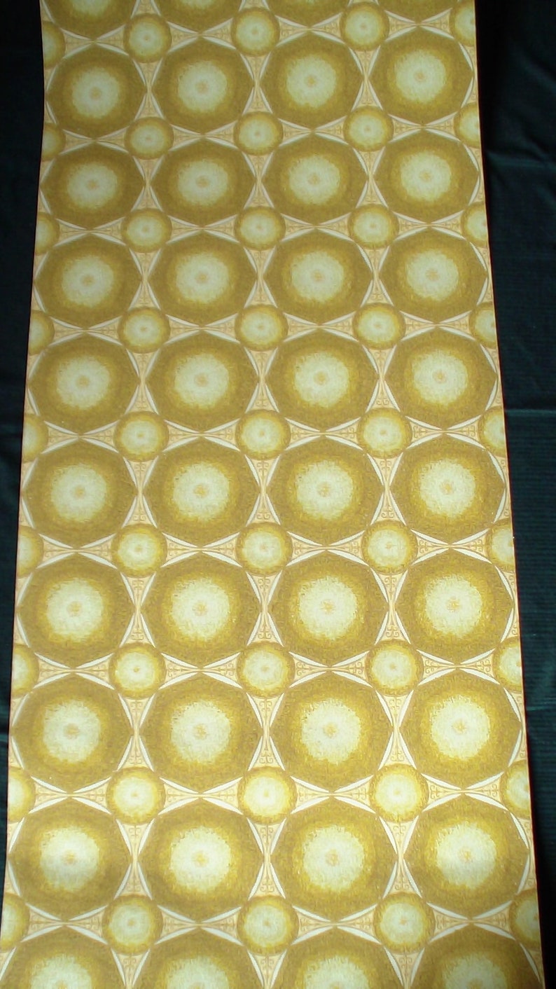 May include: A close-up of a wallpaper with a repeating pattern of white circles with a yellow center, surrounded by a brown geometric design. The wallpaper has a textured surface.