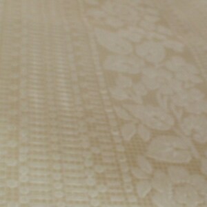 Puede incluir: Primer plano de una tela blanca con un sutil patr&oacute;n floral en relieve. La tela tiene una superficie ligeramente texturizada.