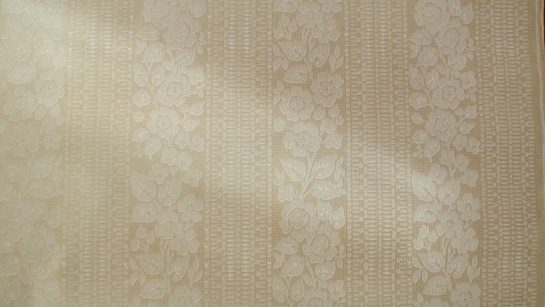 Puede incluir: Papel tapiz beige con un patr&oacute;n floral en relieve blanco. El patr&oacute;n presenta rayas verticales repetidas de flores y hojas.