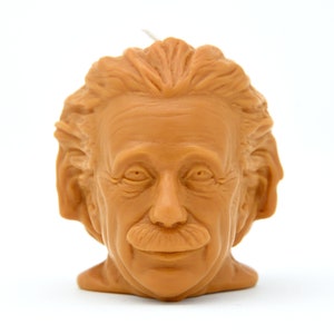 May include: A brown wax candle shaped like Albert Einstein's head. The candle has a detailed face with a mustache and a slight smile.
