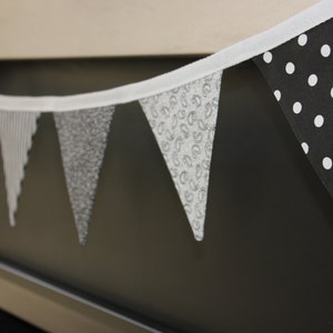 May include: A white fabric banner with black and white patterned triangles. The banner is hanging above a fireplace.