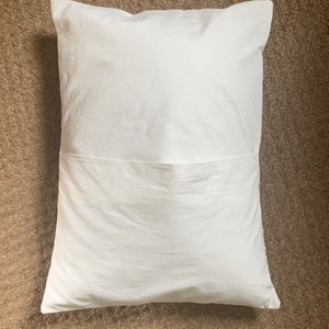 May include: A white pillow with a sewn-in pocket on the back side.