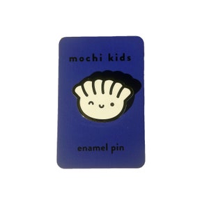 Puede incluir: Una tarjeta azul con el texto "mochi kids enamel pin" y un pin de esmalte blanco de un dumpling sonriente.