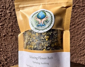May include: A brown paper pouch with a white label that reads "Relaxing Flower Bath Hydrating, Soothing Ingredients: lavender, chamomile, hibiscus, love". The pouch contains dried herbs and flowers. A sticker with a globe and the words "GAIA CRAVT" is on the front of the pouch.