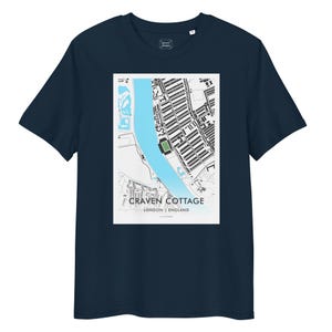 Może przedstawiać: Granatowa koszulka z czarno-białą mapą Craven Cottage w Londynie, Anglia. Mapa zawiera jasnoniebieską rzekę i zielony stadion. Tekst "CRAVEN COTTAGE" i "LONDON | ENGLAND" jest wydrukowany poniżej.