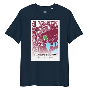 May include: Dark navy t-shirt with a graphic of Sixfields Stadium, Northampton, England. The graphic is a map-style illustration in red, white, and blue. The text "SIXFIELDS STADIUM" and "NORTHAMPTON - ENGLAND" are printed below the map.