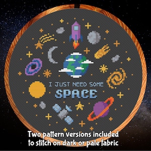 May include: A black and white cross-stitch pattern with a space theme. The pattern includes a rocket, planets, stars, and the text "I just need some space".