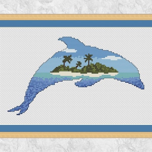 Puede incluir: Obra de arte de punto de cruz de un delfín saltando, con una escena de isla tropical dentro de su silueta. El delfín es principalmente azul, con una isla azul claro y verde con palmeras. La obra está enmarcada en un marco marrón claro con un borde interior azul.