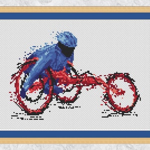 Può includere: Opera d'arte a punto croce di un ciclista in movimento. Il ciclista e la bicicletta sono raffigurati in tonalità blu e rosse su sfondo bianco. L'immagine è incorniciata con un bordo blu e una cornice marrone chiaro.