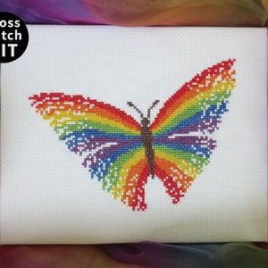 May include: Cross stitch kit featuring a rainbow butterfly design. The butterfly is stitched in shades of red, orange, yellow, green, blue, indigo, and violet.