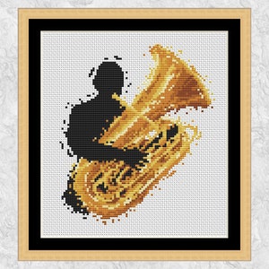 May include: Cross-stitch art of a musician playing a tuba. The silhouette of the musician is black, and the tuba is gold and yellow. The artwork is framed in a light brown frame with a black border, set against a white background.