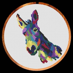 Peut inclure: Une broderie au point de croix colorée représentant la tête d'un âne. L'âne est représenté dans une palette vibrante de violet, bleu, jaune, vert et rouge.