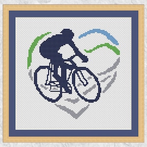 Puede incluir: Un patrón de punto de cruz de una persona montando una bicicleta en forma de corazón con acentos verdes, azules y grises.