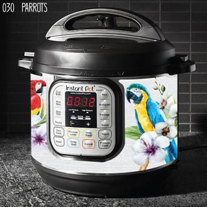 May include: White Instant Pot with a digital display showing 88:88. The Instant Pot has a black handle and a white decal with a tropical design featuring parrots and flowers.