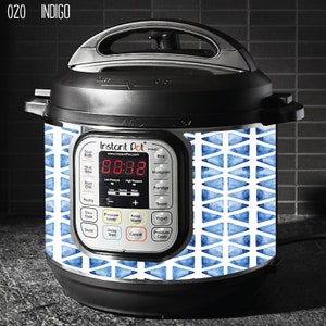 Può includere: Una pentola a pressione Instant Pot Duo con un adesivo geometrico blu e bianco. L'adesivo presenta un motivo ripetitivo di triangoli con un effetto acquerello. Il display dell'Instant Pot mostra l'ora 08:38.