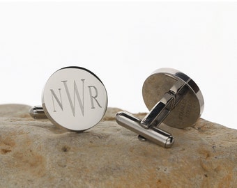 May include: A pair of silver cufflinks with a round, engraved design. The cufflinks feature the initials "NWR" in a script font. The back of one cufflink is visible, showing the words "Stainless Steel".