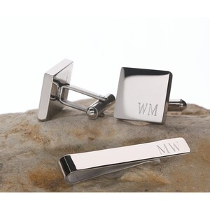 May include: A set of silver cufflinks and a tie clip with the initials "WM" engraved on each piece.