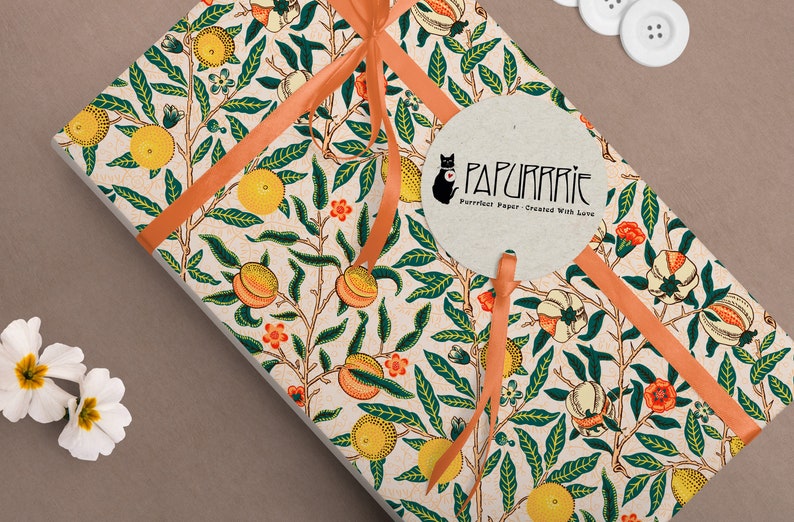 Puede incluir: Un regalo envuelto en papel estampado blanco y naranja con un dise&ntilde;o de melocot&oacute;n y hojas. El papel est&aacute; atado con una cinta de color melocot&oacute;n y una etiqueta redonda con el texto "PAPURRIE Perfect Paper - Created With Love".