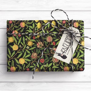 Puede incluir: Papel de regalo negro y verde con un patr&oacute;n floral de limones, granadas y hojas. El papel de regalo est&aacute; atado con una cuerda negra y blanca y una etiqueta marr&oacute;n con el texto "FARCURIA Papel perfecto para un regalo preciado".