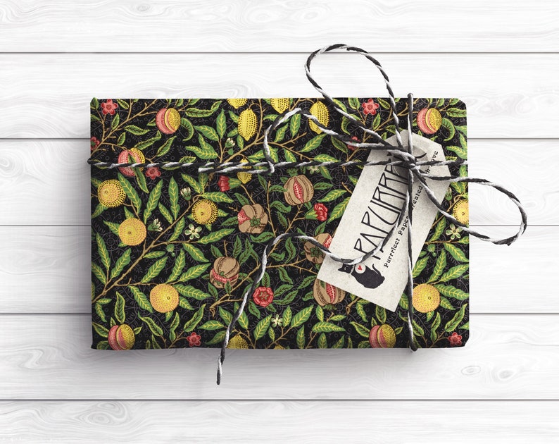 Puede incluir: Papel de regalo negro y verde con un patr&oacute;n floral de limones, granadas y hojas. El papel de regalo est&aacute; atado con una cuerda negra y blanca y una etiqueta marr&oacute;n con el texto "FARCURIA Papel perfecto para un regalo preciado".
