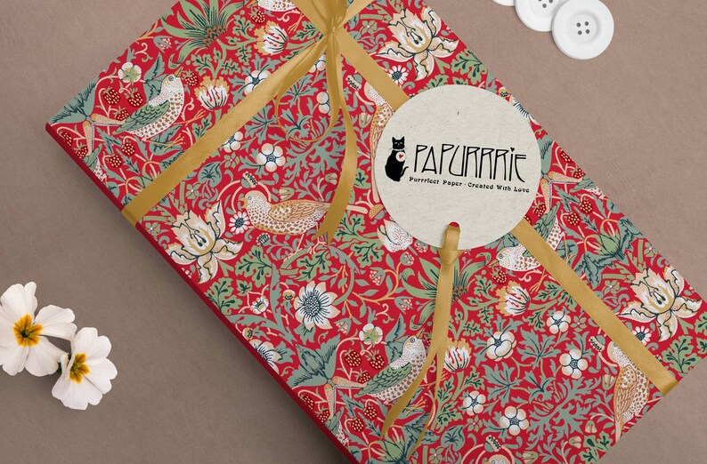 May include: A red and green patterned gift wrap with a gold ribbon and a round tag that says "PAPURRIE Perfect Paper - Created With Love".
