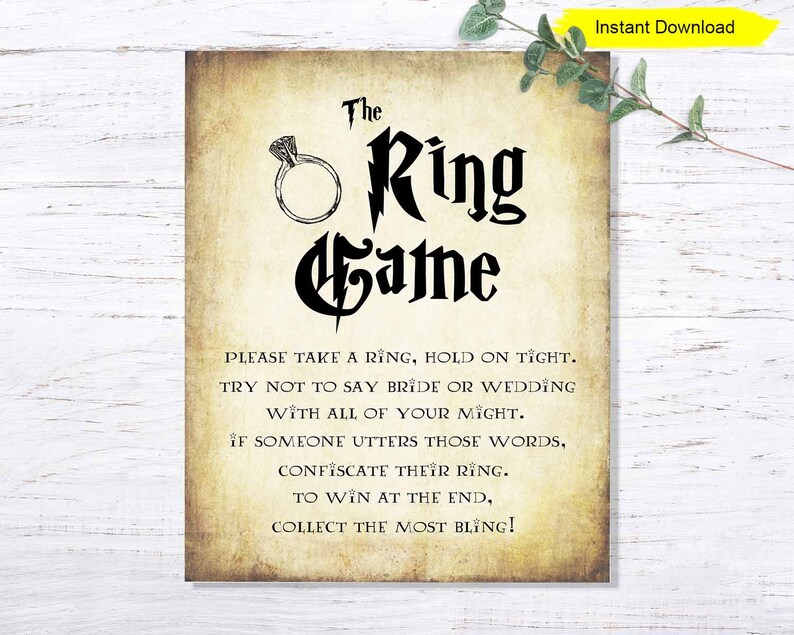 May include: A printable sign with a vintage parchment background and black text that reads "The Ring Game". The sign includes instructions for a game where guests take a ring and try not to say "bride" or "wedding".