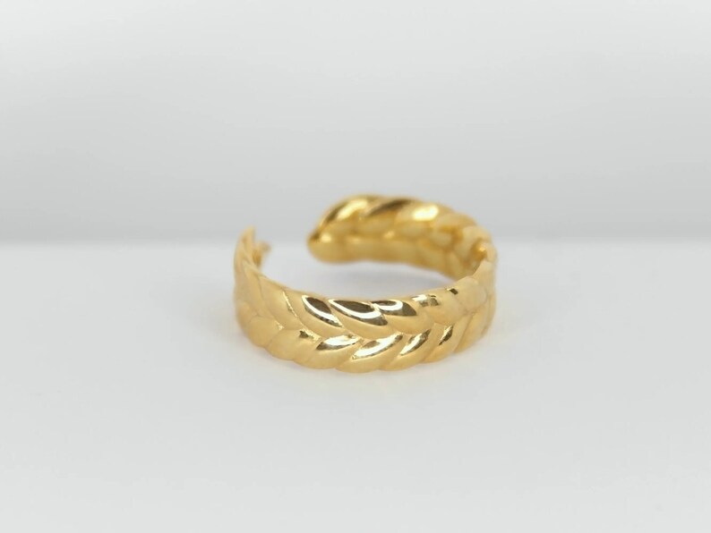 May include: A gold-toned ear cuff with a leaf-like design. The cuff is made of metal and has a smooth, polished finish.