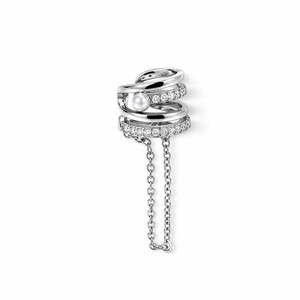 May include: A silver-toned ear cuff featuring a multi-layered band design with a single white pearl accent, a row of small clear stones, and a delicate dangling chain that connects two points of the cuff, creating a layered and textured appearance.