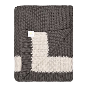 May include: A gray and white striped knitted throw blanket. The blanket is folded in half and the label "The  Company Store" is visible.