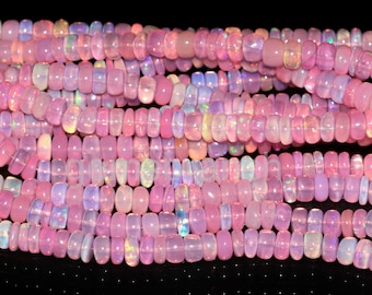 May include: Close-up of strands of pink opal beads. The beads are a mix of shapes and sizes, with a soft, iridescent sheen. The color palette ranges from pale pink to deeper rose, with hints of blue and yellow.