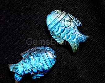 Puede incluir: Dos tallas de peces de labradorita azul iridiscente. Los peces están tallados con escamas y aletas detalladas.