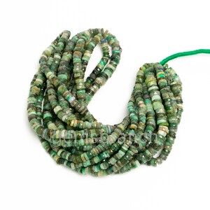 May include: A strand of green gemstone beads, likely emerald or green opal, with a faceted, slightly irregular shape. The beads are strung on a thin green thread.