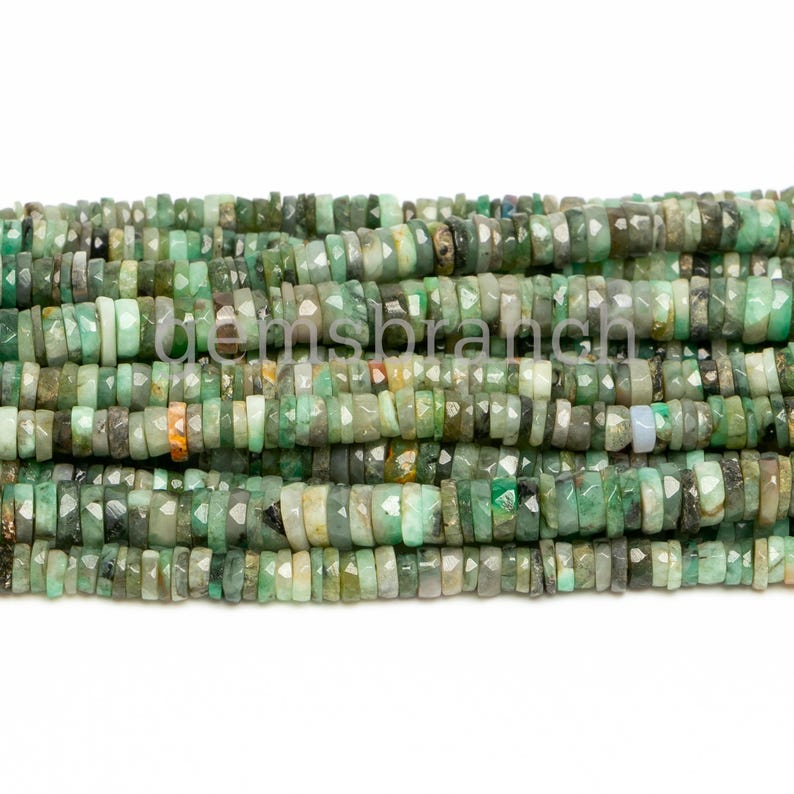 May include: A strand of emerald green faceted beads, each bead is a different shape and size, with some beads having a more opaque appearance.