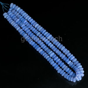 May include: A strand of light blue gemstone beads. The beads are round and have a slightly irregular shape. The beads are strung on a clear thread.