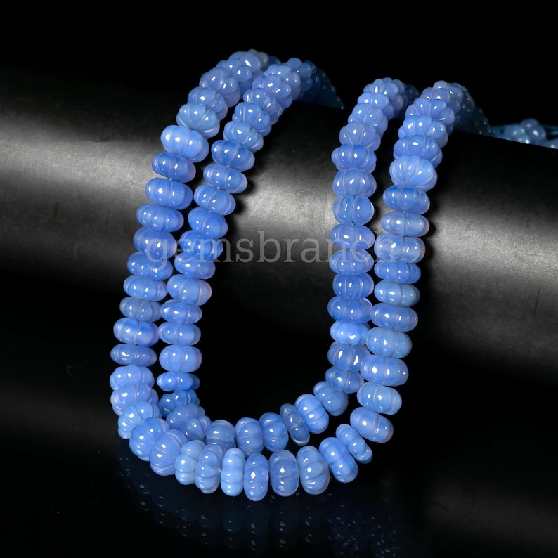 May include: A strand of light blue chalcedony beads. The beads are faceted and have a slightly bumpy texture. The beads are strung on a clear elastic cord.