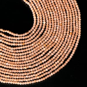 May include: A strand of peach-coloured sunstone beads, faceted and strung together. The beads are small and uniform in size, creating a smooth and elegant look.
