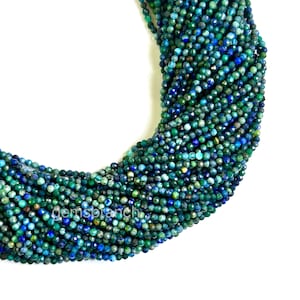 Può includere: Un filo di perle di pietre preziose blu e verdi. Le perle sono piccole e rotonde, e hanno una finitura sfaccettata. Le perle sono infilate su un filo trasparente.