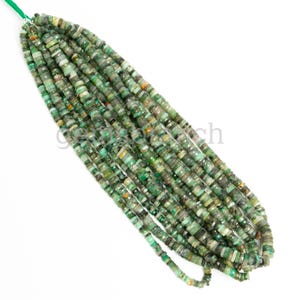 May include: A strand of green emerald gemstone beads. The beads are faceted and have a slightly irregular shape. The beads are strung on a clear thread.