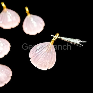 Op de afbeelding: Lichtroze, bloemblad-vormige edelsteenhangers met goudkleurige beugels. De hangers zijn gesneden met delicate lijnen en worden weergegeven tegen een zwarte achtergrond. De tekst "Ge an ch" is zichtbaar.