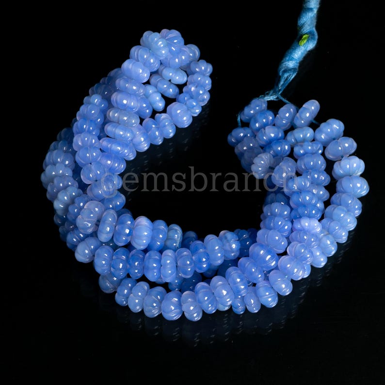 May include: A strand of light blue chalcedony beads, each bead is shaped like a flower with multiple rounded petals. The beads are strung together in a continuous loop.