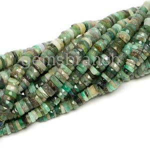 May include: A strand of green emerald gemstone beads. The beads are faceted and have a slightly irregular shape. They are strung on a clear thread.