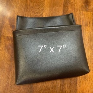 May include: A black leather pouch with a 7" x 7" measurement printed on the front.