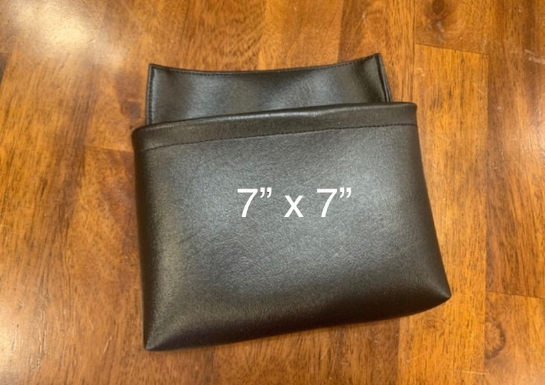 May include: A black leather pouch with a 7" x 7" measurement printed on the front.