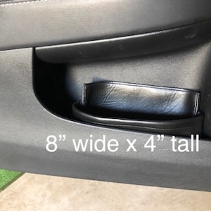 May include: Black leather car door organizer with a 8" wide x 4" tall measurement.