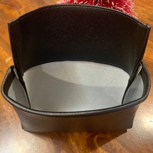 May include: A black leather pouch with a white fabric lining. The pouch is open and empty.