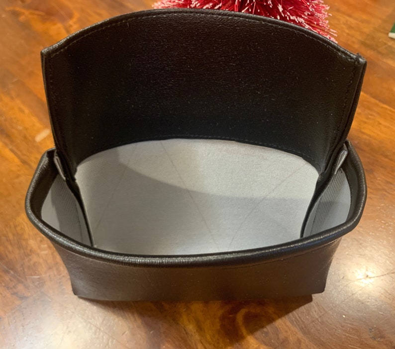 May include: A black leather pouch with a white fabric lining. The pouch is open and empty.