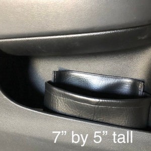 May include: Black leather car door organizer with a 7" by 5" tall measurement.